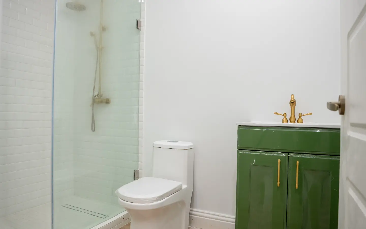 Bathroom with a glass walk-in shower, brass fixtures and a green vanity at Casa Playa 315