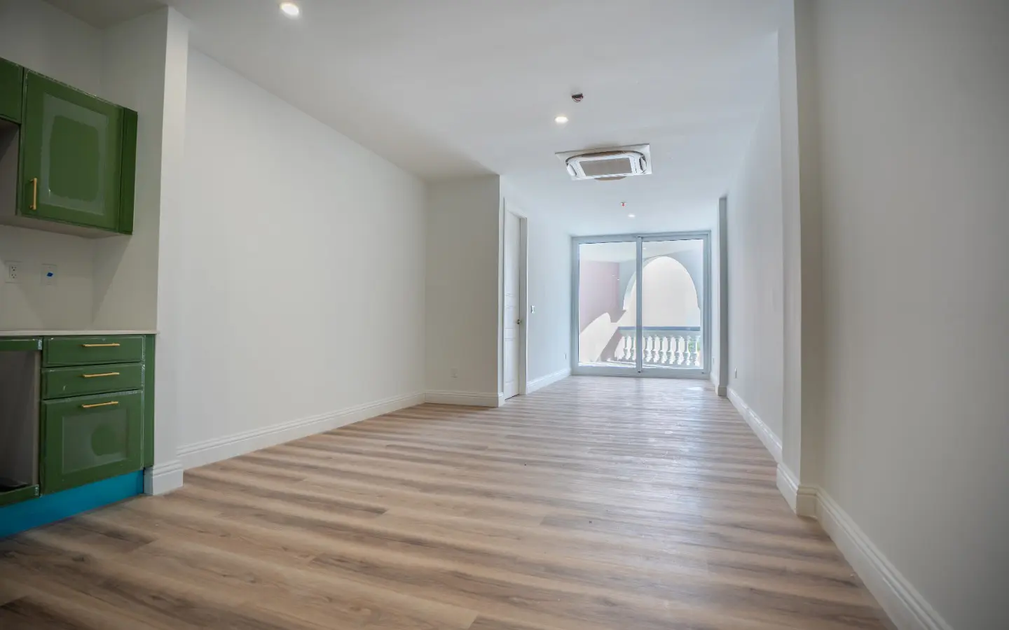 Interior of Casa Playa Unit 315 with wood-look flooring and natural light from the terrace door
