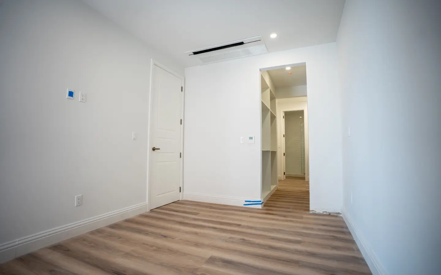 Walk-through closet with full-height shelving leading to the tiled bathroom beyond