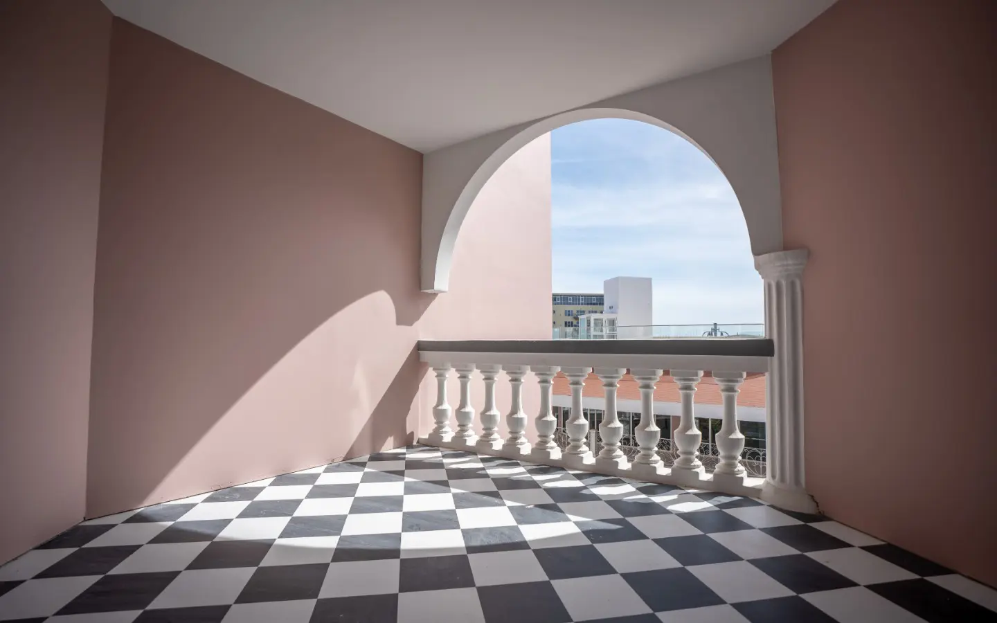 Private arched terrace with a chequerboard tile floor and white balustrade at Casa Playa 315