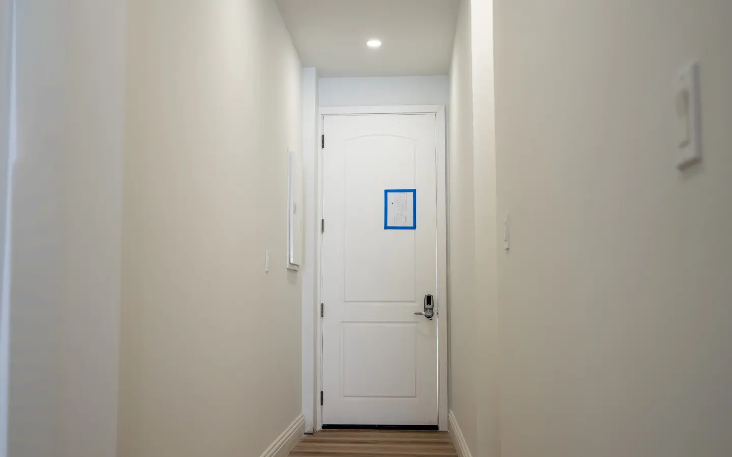 Entrance hallway of Unit 315 leading to the front door fitted with a keypad smart lock
