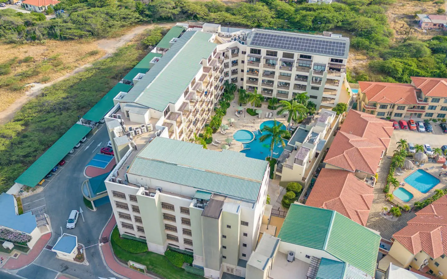 Overhead aerial of the community pool, tennis court and parking at PalmAruba, Aruba