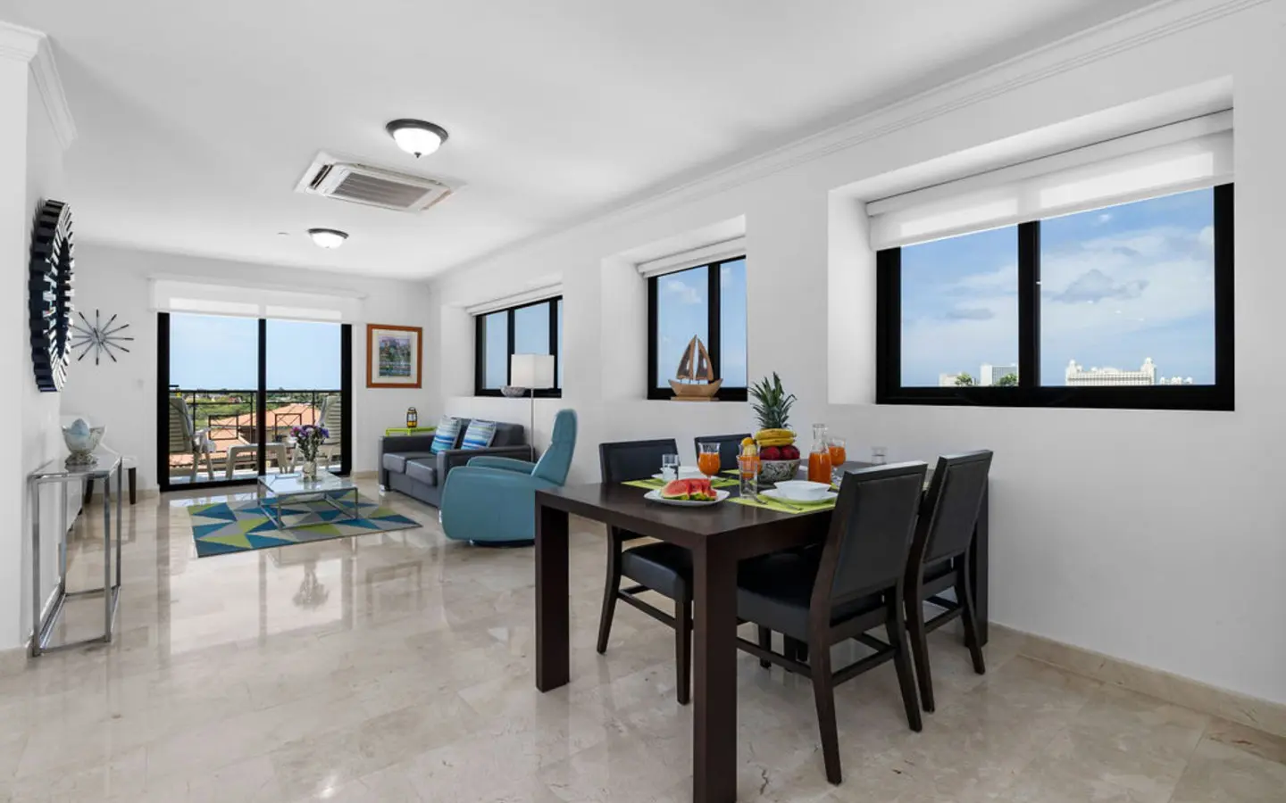 Dining area for six beside the living room, lit by a row of windows in the Palm Beach condo