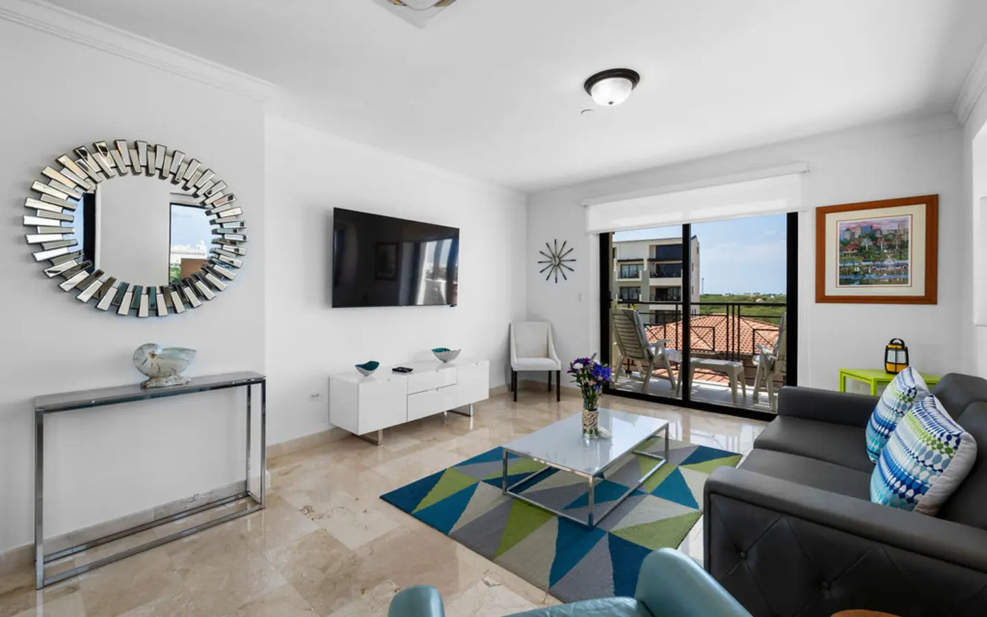 Living room with wall-mounted TV and sliding doors to the private balcony in PalmAruba 418