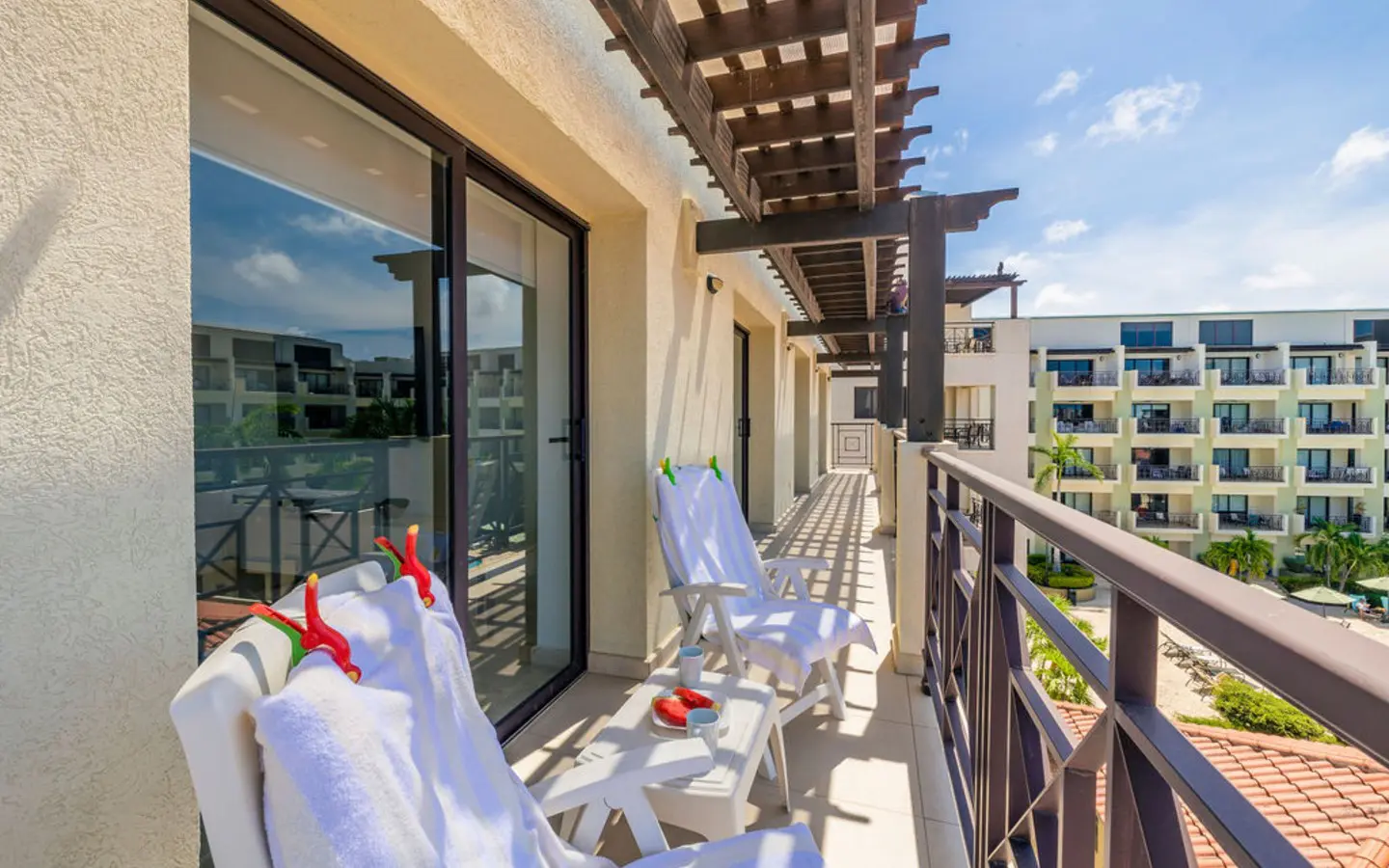Private balcony with loungers under a wooden pergola, overlooking the condo grounds