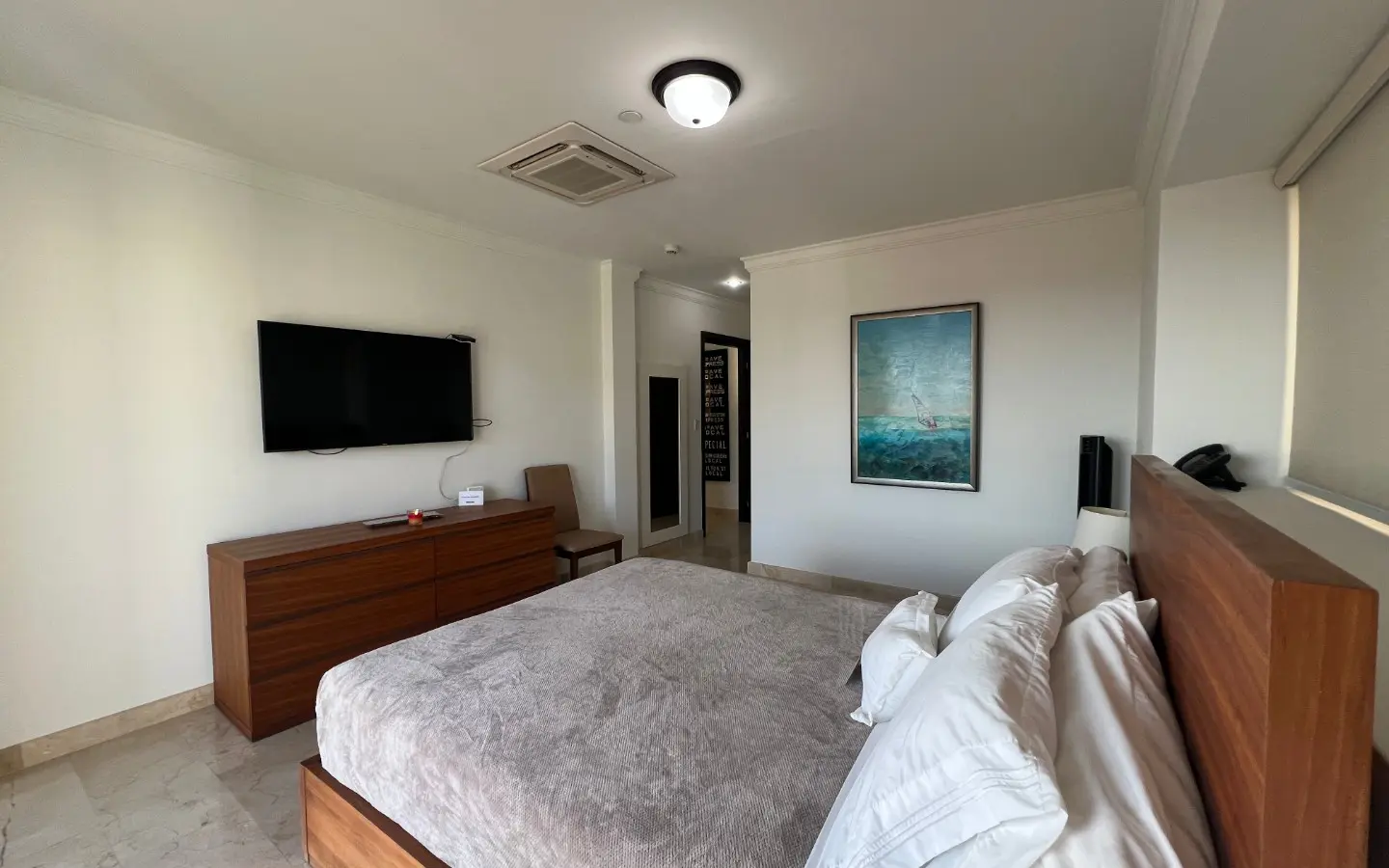 Second view of the master bedroom showing the dresser, wall-mounted TV and hallway