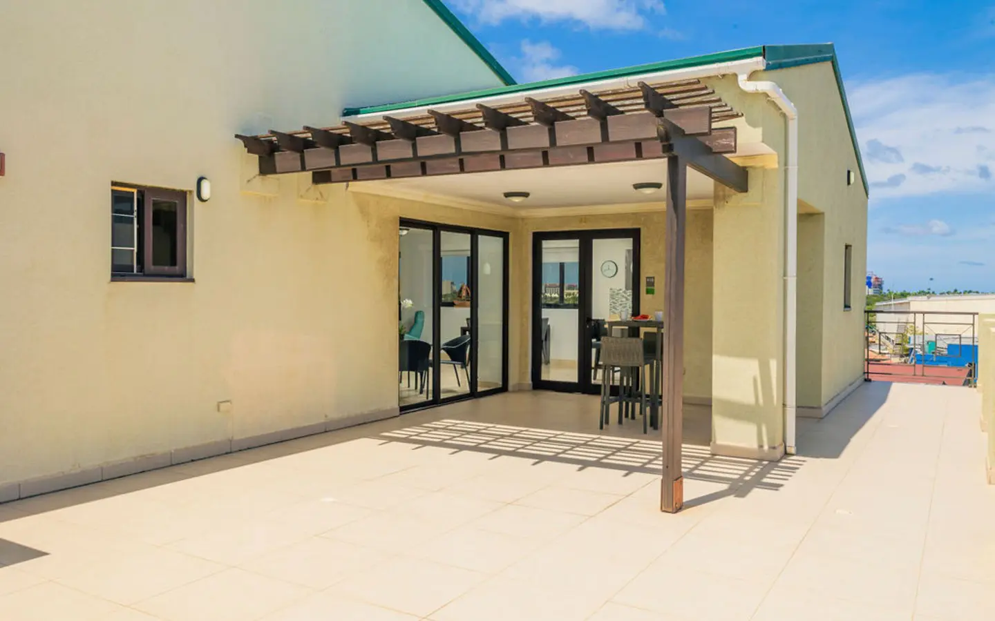 Covered terrace and the entrance to unit 418, with a wicker bar table and seating