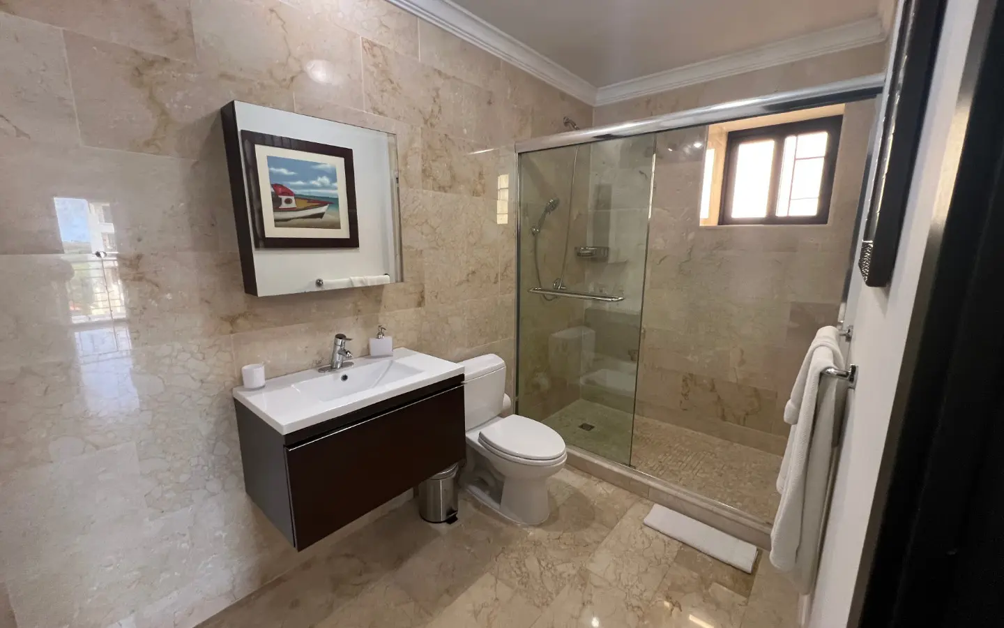 Second full bathroom finished in marble with a glass shower enclosure