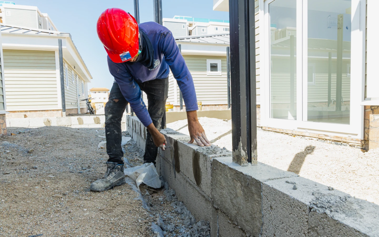 Mason laying the block course beside a villa terrace door at Caribbean Town