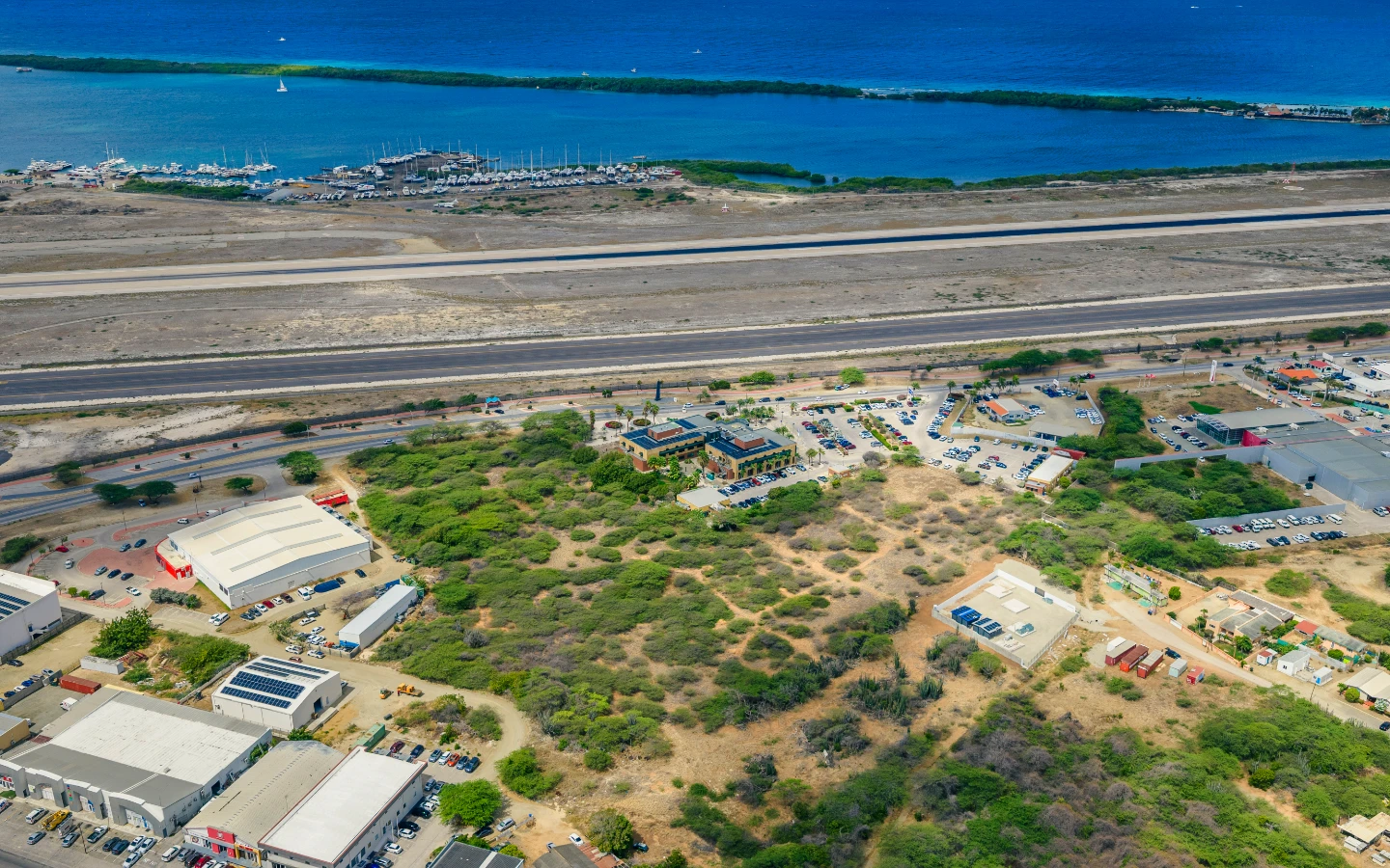 Aerial of the Camacuri land with the airport runway, marina and Caribbean Sea in the distance